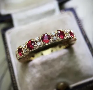 Macro detail of a vintage style gold plated ring featuring red and white zircons