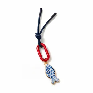 Detailed view of a blue and white floral pattern fish charm attached to a red carabiner