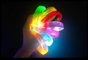 Detailed view of colorful glowing LED acrylic bracelets held in hand against dark background