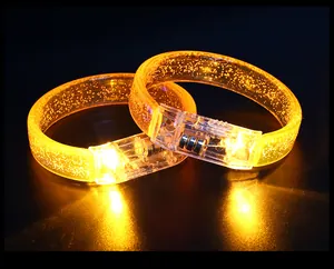 Macro view of two glowing orange acrylic LED bracelets with glitter effect for concert parties