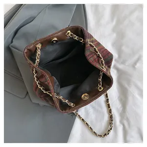 Détail du sac seau rétro en laine à carreaux montrant la poche zippée et le fermoir magnétique