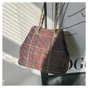 Vue détaillée d'un sac seau en laine à carreaux vintage avec des lanières en chaîne dorée