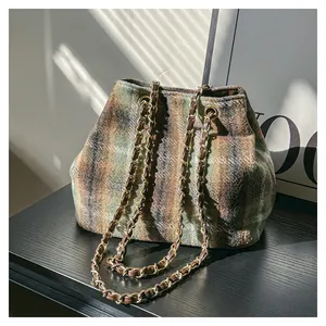 Vue détaillée du sac seau en laine à carreaux avec chaîne dorée et ombre naturelle.