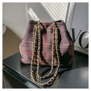 Détail d'un sac seau vintage en laine à carreaux avec bandoulière en chaîne dorée