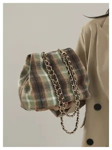 Détail de ce sac seau en laine à carreaux avec d'élégantes bandoulières dorées