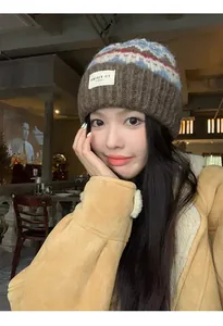 Asian woman wearing a retro brown knitted beanie with a pattern in a warm cafe.