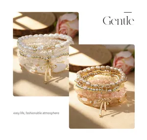 Detailed view of Bohemian stacked bracelets with faux pearls and gold bow charms.