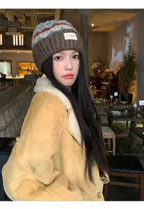 A close-up view of a vintage knitted beanie hat worn by a model in a cozy cafe setting.