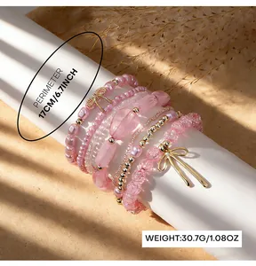 Close-up detail of bohemian layered pink glass bead bracelet set with gold bow charms