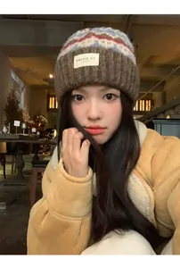 Close-up of a vintage multi-color knitted beanie hat worn by an Asian model in a cozy cafe setting