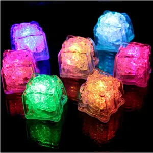 Close-up of colorful LED glowing ice cubes on a dark reflective surface for bar decor