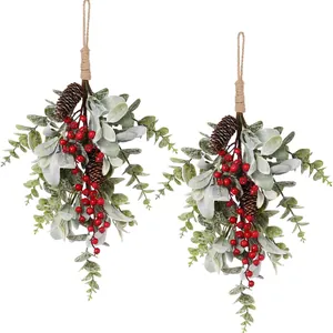 Detailed view of two Christmas swags with faux leaves, red berries, and pine cones.