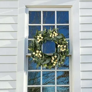 Detailed view of the large eucalyptus and ivory berry wreath hanging on a white window frame.