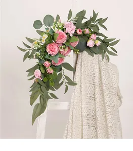 Detail of artificial pink rose and greenery swag draped over a vintage white ladder.