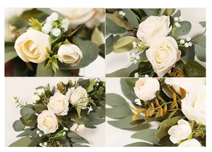 Close-up details of artificial white roses and eucalyptus leaves for wedding decor.