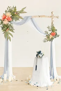 Floral arch decor with peach artificial flowers and blue drapes for wedding ceremony