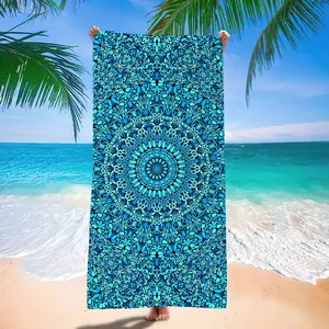Blue mandala pattern microfiber quick-dry beach towel displayed on a tropical sandy beach