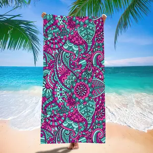 Full view of a vibrant mandala patterned microfiber quick-dry beach towel on a sunny beach