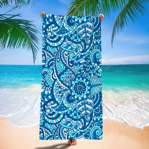 Vibrant blue mandala pattern on a quick-dry microfiber beach towel shown in a seaside view.