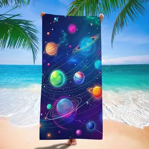 Galaxy print microfiber beach towel with vibrant planets and orbital rings on a sunny beach.