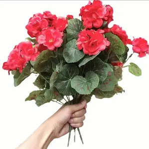 Close-up of vibrant red artificial geranium silk flowers held by hand for home decor display
