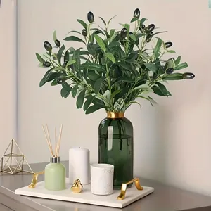 Macro view of realistic artificial olive branches with fruits in a stylish green glass vase