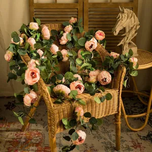 Artificial peony and eucalyptus flower garland draped over a rustic wicker chair decor.