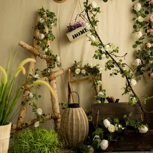 Detail view of artificial white peony flower vines with eucalyptus leaves in rustic setting.