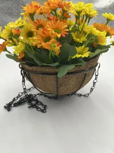 Close-up of yellow and orange artificial daisies in a coco coir hanging basket.