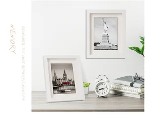 Due cornici per foto in legno bianco in un allestimento minimalista su tavolo e parete