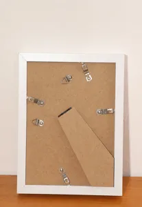 Detailed rear view of white wooden shadow box frame showing wall hooks and folding stand