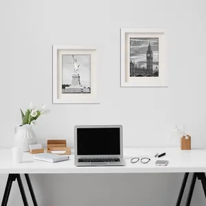 Due cornici per foto A4 in legno bianco minimalista su una scrivania da ufficio.