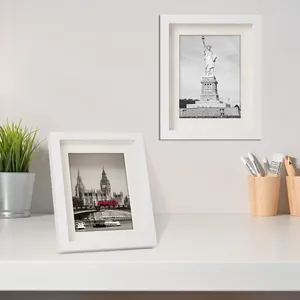 Due cornici per foto A4 minimaliste in legno bianco esposte in un ambiente ufficio pulito