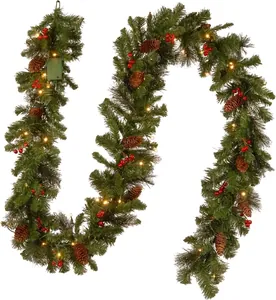 Close-up detail of pre-lit Christmas pine garland with pinecones and red berries for holiday decor