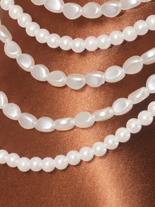 Macro detail of elegant multi-layer faux pearl halter top on shimmering bronze satin.