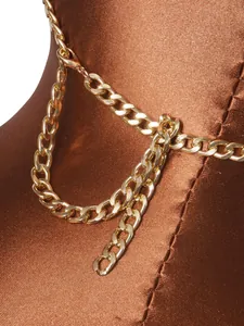 Detailed close-up showing a shiny layered gold metal chain on brown satin fabric garment