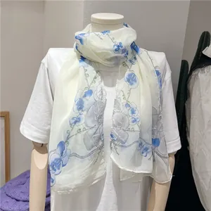 Close-up view of a lightweight white chiffon long scarf with blue orchid floral pattern