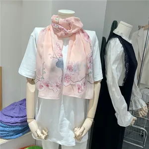 Detail of pink chiffon scarf with floral and magpie print on mannequin