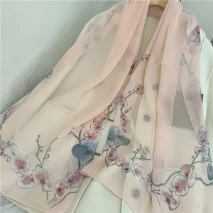 Detail view showing the delicate orchid flower print on a soft pink chiffon scarf texture.