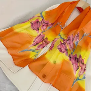 Detail view of vibrant orange and yellow chiffon long scarf with pink floral prints