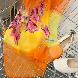 Detail of long chiffon scarf with vibrant floral print in orange and yellow gradient