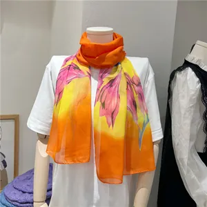 Close-up detail of lightweight orange chiffon long scarf with pink lily floral print