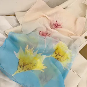 Close-up view of elegant floral print chiffon scarves in soft blue and beige tones.