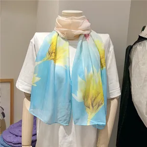 Close-up detail of a light blue chiffon long scarf with vibrant yellow floral prints.