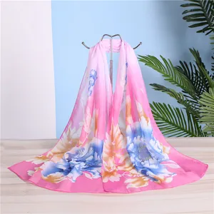 Detailed view of an elegant long pink chiffon scarf with vibrant floral print on a rack