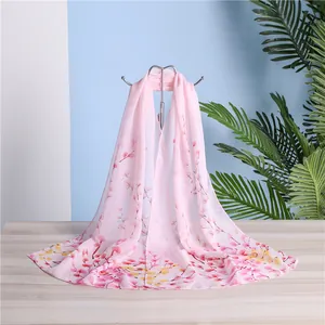 Close-up detail of a lightweight pink chiffon long scarf with vibrant floral prints