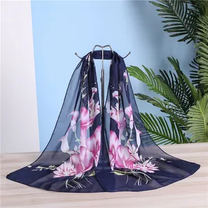 Detailed macro view of long navy blue chiffon scarf with elegant pink lily print