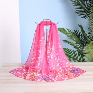 Detailed view of a vibrant pink floral chiffon scarf on a silver display stand.