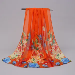 Detail of an orange chiffon scarf featuring vibrant floral and peacock feather prints.