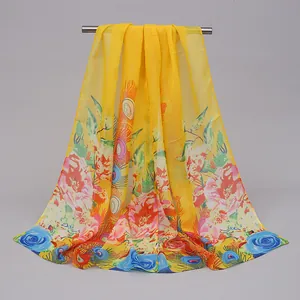 Detailed view of long yellow chiffon scarf with vibrant floral and peacock prints